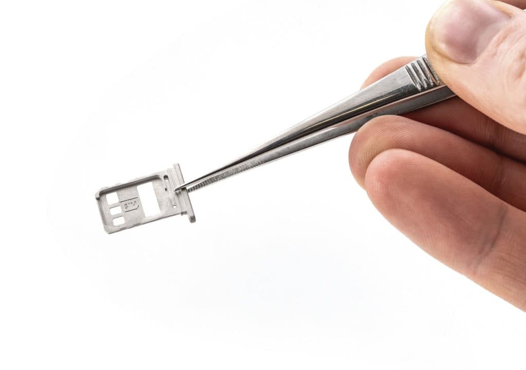 Hand holding a micro SD card tray with tweezers