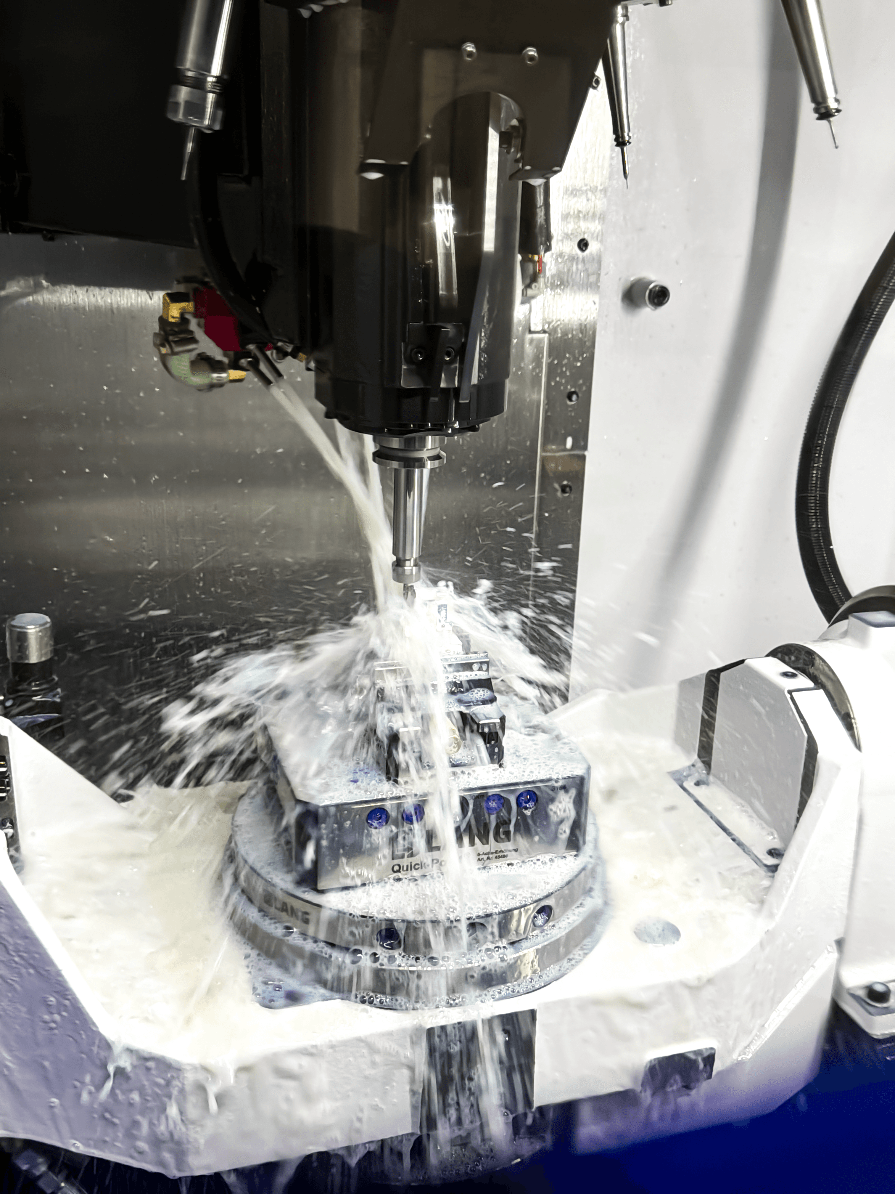 5-axis CNC machine cutting a metal part under flood coolant